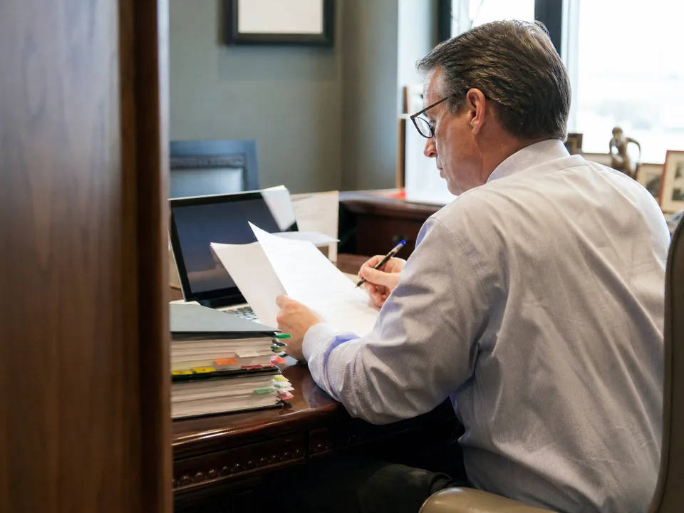 Litigation partner reviewing a printed software proposal at a desk beside tabbed case binders