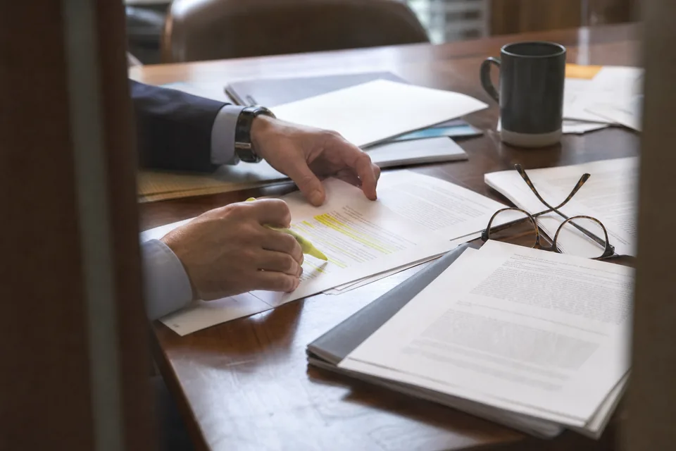 Lawyer's hands highlighting passages in a printed court opinion next to a draft motion with footnotes