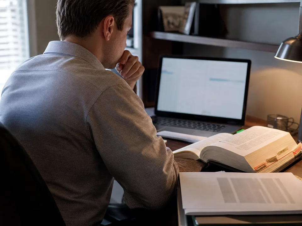 Tax attorney researching on a laptop beside a tabbed federal tax code volume during tax season