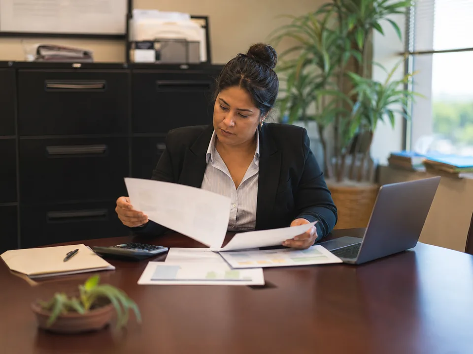Public defender office manager reviewing a software contract and budget sheet at a conference table